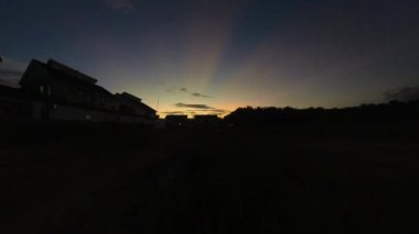 Boş arazinin yakınındaki yerleşim yerindeki altın saat sahnesinin hızlandırılmış görüntüleri..  