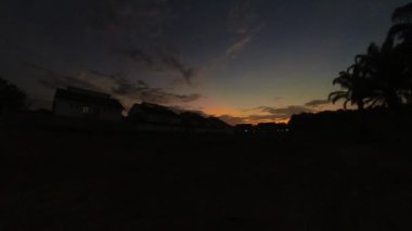 Boş arazinin yakınındaki yerleşim yerindeki altın saat sahnesinin hızlandırılmış görüntüleri..  