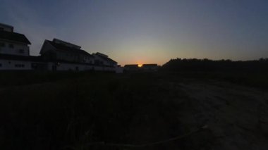 Boş arazinin yakınındaki yerleşim yerindeki altın saat sahnesinin hızlandırılmış görüntüleri..  