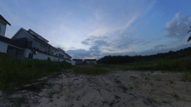 Boş arazinin yakınındaki yerleşim yerindeki altın saat sahnesinin hızlandırılmış görüntüleri..  