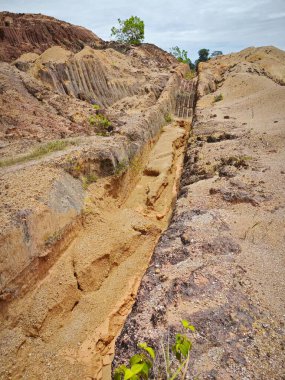 Ormanların tahrip edilmesi ve toprak madenciliği nedeniyle terk edilmiş boş arazinin çevresinde dramatik bir manzara var.. 