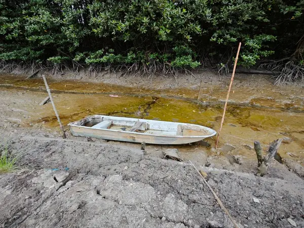 stock image wooden dingy docked around the vicinity of the dried or low tide river outside the charcoal factory shed.