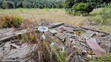 Tarım arazisindeki eski barakanın dışına çöpleri atmışlar..