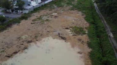 Büyük bir yağmur suyu birikintisi olan bir adamın yerleşim yerinin yakınlarında dikilirken çekilmiş görüntüleri..  