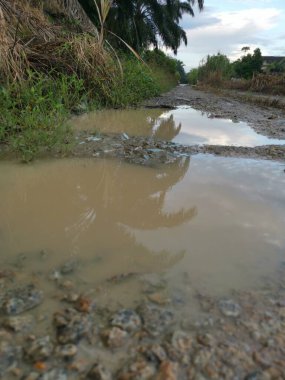 reflective pool of stagnant water after heavy rainfall on the rural dirt road.  