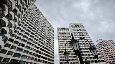 Gökyüzüne bakıyorum, gökyüzü mavi gökyüzü yüksek binalar, balkon deseni ve ön plandaki yapı..