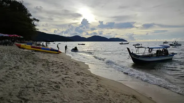 Penang, Malezya. 10 Kasım 2024: Batu Ferringhi sahilindeki kumlu sahil manzarası ve yerel eğlence etkinliği.