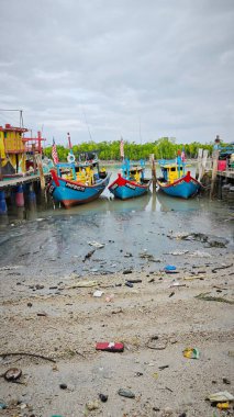 Perak, Malezya. 3 Aralık 2024: Pantai Remis Village Liman Güvertesi 'ndeki balıkçılık gezisinden döndükten sonra beton iskeleye yanaşan balıkçı teknelerinin görüntüsü. 