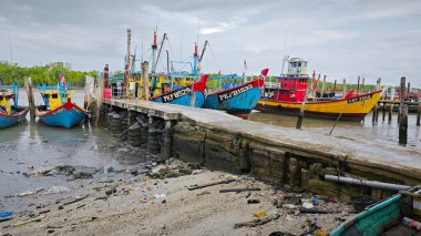 Perak, Malezya. 3 Aralık 2024: Pantai Remis Village Liman Güvertesi 'ndeki balıkçılık gezisinden döndükten sonra beton iskeleye yanaşan balıkçı teknelerinin görüntüsü. 