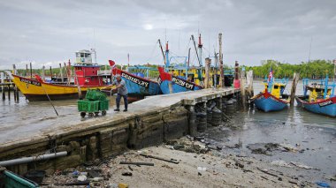 Perak, Malezya. 3 Aralık 2024: Pantai Remis Village Liman Güvertesi 'ndeki balıkçılık gezisinden döndükten sonra beton iskeleye yanaşan balıkçı teknelerinin görüntüsü. 