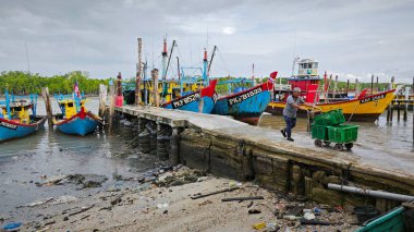 Perak, Malezya. 3 Aralık 2024: Pantai Remis Village Liman Güvertesi 'ndeki balıkçılık gezisinden döndükten sonra beton iskeleye yanaşan balıkçı teknelerinin görüntüsü. 