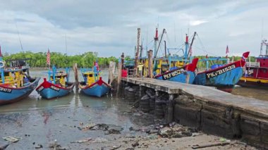 Perak, Malezya. 3 Aralık 2024: Pantai Remis Village Liman Güvertesi 'ndeki balıkçılık gezisinden döndükten sonra beton iskeleye yanaşan balıkçı teknelerinin görüntüsü. 