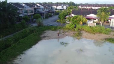 Erkek modelin, yerleşim yerinin etrafındaki durgun yağmur suyu göletinde uçan dron görüntüsü..