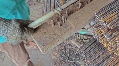 Paslı metal çubuğu bükerek inşaat kullanımı için kare şeklindeki çelik şebekeye dönüştüren birinin video klibi.. 