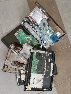 Perak,Malaysia. February 13,2025: Pile of spoiled dissemble laptop motherboard components thrown on the floor at the Sitiawan Electronic Workshop. clipart