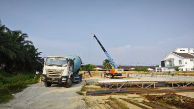 Perak, Malezya. 18 Şubat 2025: Permai 'nin yeni konut şantiyesi çevresindeki transit mikser kamyonundan karışık beton taşıyan vinç servis pompa kamyonu sahnesi. Kg Koh..
