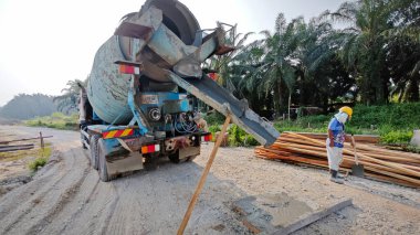 Perak, Malezya. 18 Şubat 2025: Permai 'nin yeni konut şantiyesi çevresindeki transit mikser kamyonundan karışık beton taşıyan vinç servis pompa kamyonu sahnesi. Kg Koh..