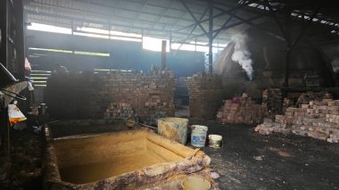 Perak,Malaysia.February 25, 2025: Scene  of laborer building and repairing an indoor igloo-shaped kiln at Kg Kelubung Charcoal factory.  clipart