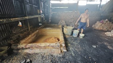 Perak,Malaysia.February 25, 2025: Scene  of laborer building and repairing an indoor igloo-shaped kiln at Kg Kelubung Charcoal factory.  clipart