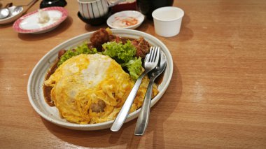 Bir tabak pilav sarılmış yumurta, sebze salatası ve Japon körili kızarmış tavuk eti. .  