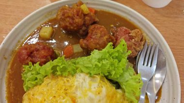 Bir tabak pilav sarılmış yumurta, sebze salatası ve Japon körili kızarmış tavuk eti.. 