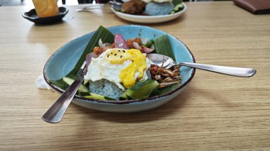 Bir tabak mor pilav, kızarmış yumurta, kıymalı tavuk eti, ançüez ve baharatlı sos..