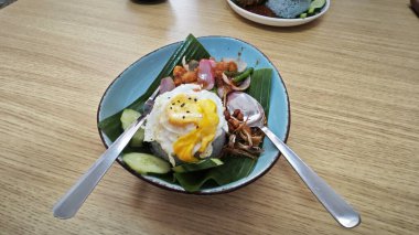 Bir tabak mor pilav, kızarmış yumurta, kıymalı tavuk eti, ançüez ve baharatlı sos..