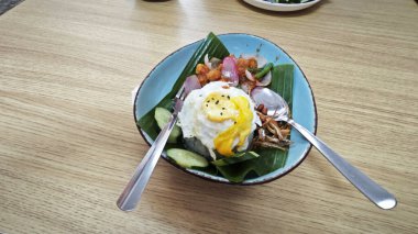 Bir tabak mor pilav, kızarmış yumurta, kıymalı tavuk eti, ançüez ve baharatlı sos..