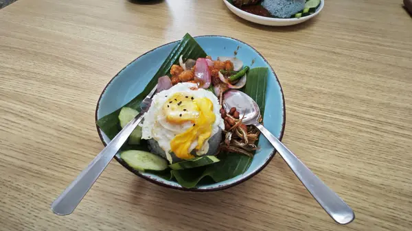 Bir tabak mor pilav, kızarmış yumurta, kıymalı tavuk eti, ançüez ve baharatlı sos..