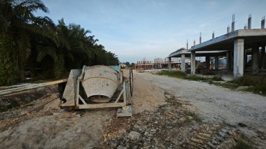 İnşaat alanındaki kum yığınının yanında eski bir çimento karıştırma makinesi..