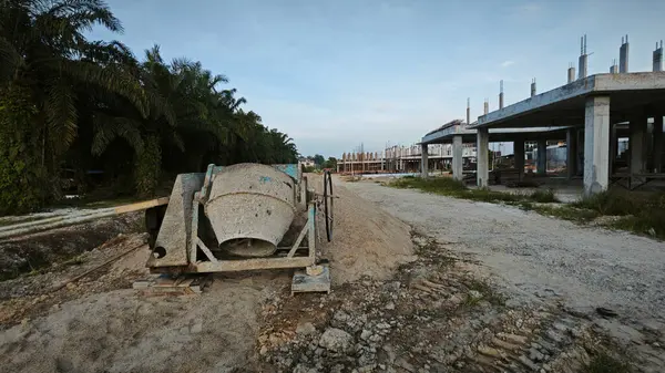 İnşaat alanındaki kum yığınının yanında eski bir çimento karıştırma makinesi..