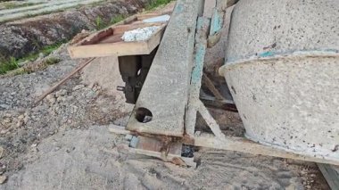 İnşaat alanındaki kum yığınının yanında eski bir çimento karıştırma makinesi..