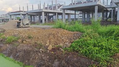 İnşaat alanındaki kum yığınının yanında eski bir çimento karıştırma makinesi..