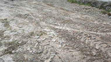 Kirli yolun yüzeyinde bilinmeyen araç tekerlek izleri var..