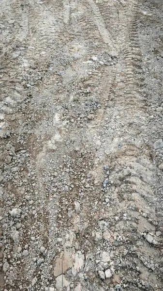 Kirli yolun yüzeyinde bilinmeyen araç tekerlek izleri var..