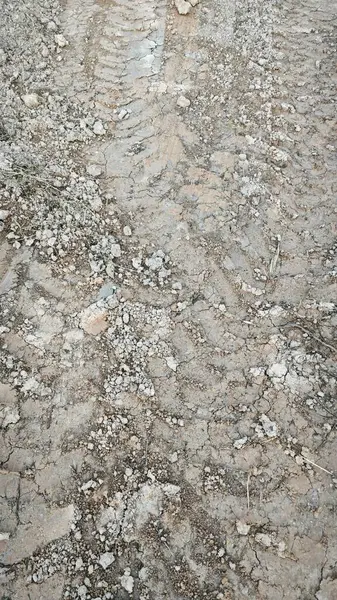 Kirli yolun yüzeyinde bilinmeyen araç tekerlek izleri var..