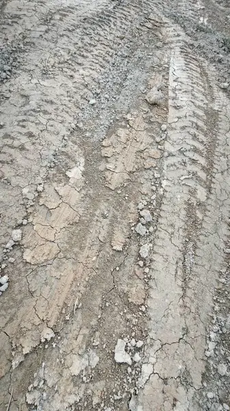 Kirli yolun yüzeyinde bilinmeyen araç tekerlek izleri var..