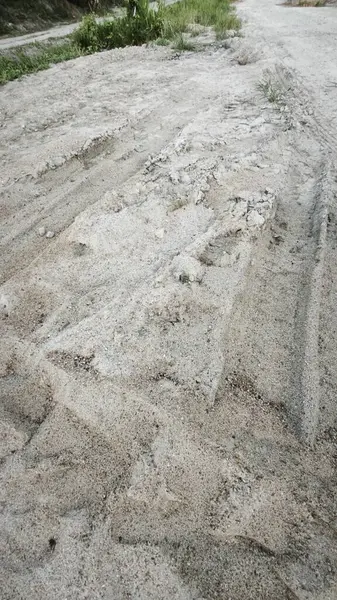 Kirli yolun yüzeyinde bilinmeyen araç tekerlek izleri var..