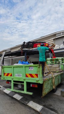 Perak, Malezya. 30 Mayıs 2025: Hooklift kamyon parkının manzarası çift katlı verandanın içinde yenileme malzemelerini Taman Mas 1, Kg koh 'un üst katındaki balkona taşıyor.. 