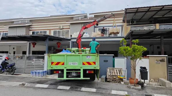 Perak, Malezya. 30 Mayıs 2025: Hooklift kamyon parkının manzarası çift katlı verandanın içinde yenileme malzemelerini Taman Mas 1, Kg koh 'un üst katındaki balkona taşıyor.. 
