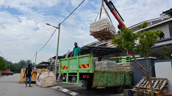 Perak, Malezya. 30 Mayıs 2025: Hooklift kamyon parkının manzarası çift katlı verandanın içinde yenileme malzemelerini Taman Mas 1, Kg koh 'un üst katındaki balkona taşıyor.. 