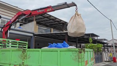 Perak, Malezya. 30 Mayıs 2025: Hooklift kamyon parkının manzarası çift katlı verandanın içinde yenileme malzemelerini Taman Mas 1, Kg koh 'un üst katındaki balkona taşıyor.. 