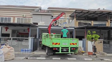 Perak, Malezya. 30 Mayıs 2025: Hooklift kamyon parkının manzarası çift katlı verandanın içinde yenileme malzemelerini Taman Mas 1, Kg koh 'un üst katındaki balkona taşıyor.. 