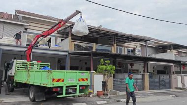 Perak, Malezya. 30 Mayıs 2025: Hooklift kamyon parkının manzarası çift katlı verandanın içinde yenileme malzemelerini Taman Mas 1, Kg koh 'un üst katındaki balkona taşıyor.. 