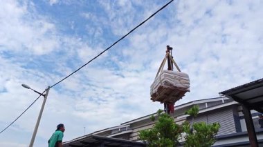 Perak, Malezya. 30 Mayıs 2025: Hooklift kamyon parkının manzarası çift katlı verandanın içinde yenileme malzemelerini Taman Mas 1, Kg koh 'un üst katındaki balkona taşıyor.. 