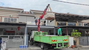 Perak, Malezya. 30 Mayıs 2025: Hooklift kamyon parkının manzarası çift katlı verandanın içinde yenileme malzemelerini Taman Mas 1, Kg koh 'un üst katındaki balkona taşıyor.. 