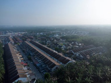 Palmiye yağı tarlasının eteklerindeki uzak evlerin hava görüntüleri..