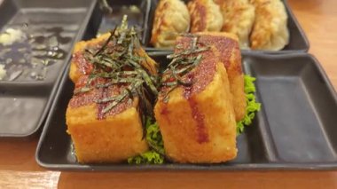 Bir tabak kızarmış Japon tofusu, kızarmış soğan dilimleri ve bir tabak daha kızarmış doğulu Dim Sum dürümü..