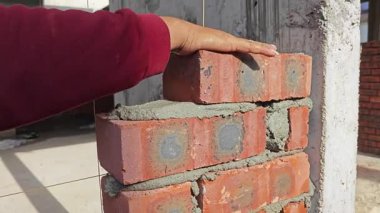 Perak, Malezya. 21 Haziran 2025: Taman Indah Permai şantiyesindeki inşaat duvarını inşa eden ve kapalı alanda çimento ve tuğla taşıyan işçilerin görüntüleri.