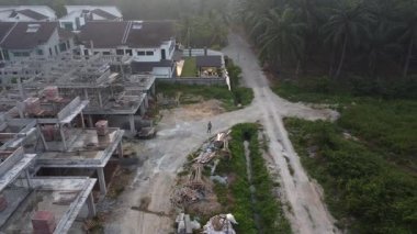 Hala yapım aşamasında olan boş arazinin etrafında insansız hava aracı uçuran bir adamın hava görüntüleri..  